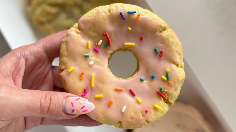 Close-up of a hand holding a Crumbl Pink Doughnut cookie