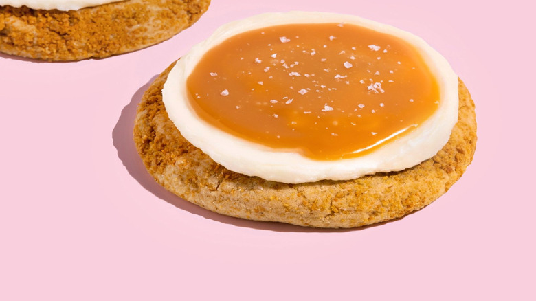 close up of the salted caramel cheesecake cookie from Crumbl on pink background