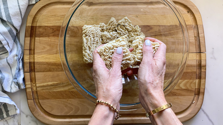 hands breaking instant ramen noodles 