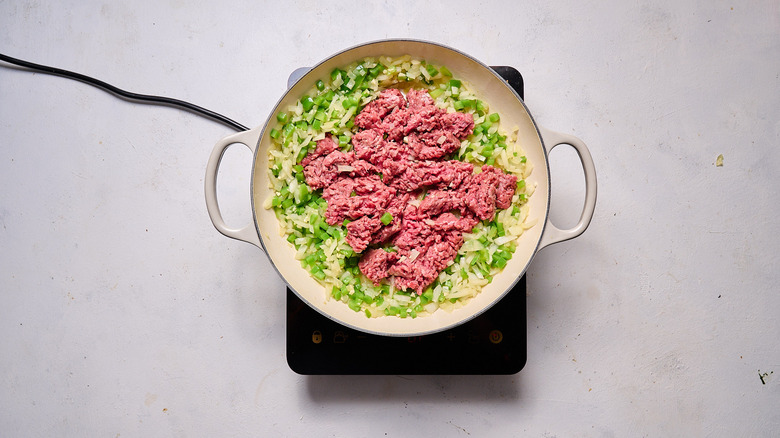 crumbling beef into skillet of vegetables