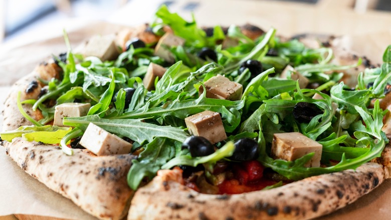 pizza with tofu, arugula, and olives