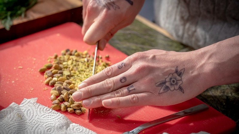 tattooed  hands chopping pistachios