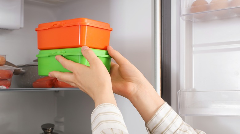 Woman putting containers in refrigerator