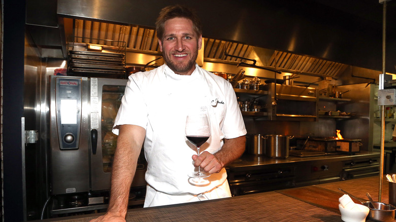 Curtis Stone smiling and holding wine at Maude