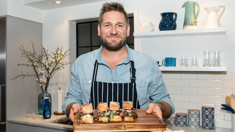 Curtis Stone holding sandwiches