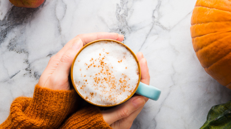 Hands wrapped around pumpkin coffee