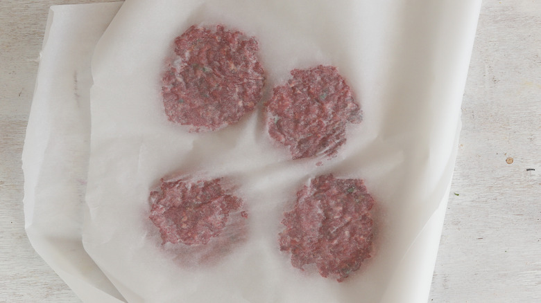 beef patties between parchment paper