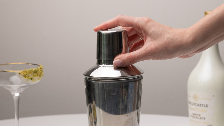 hand placing lid on cocktail shaker