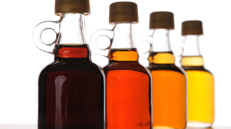 four glass bottles of maple syrup displaying different color grades