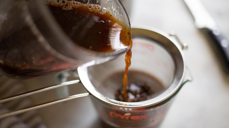 reserved liquid being poured through a mesh sieve