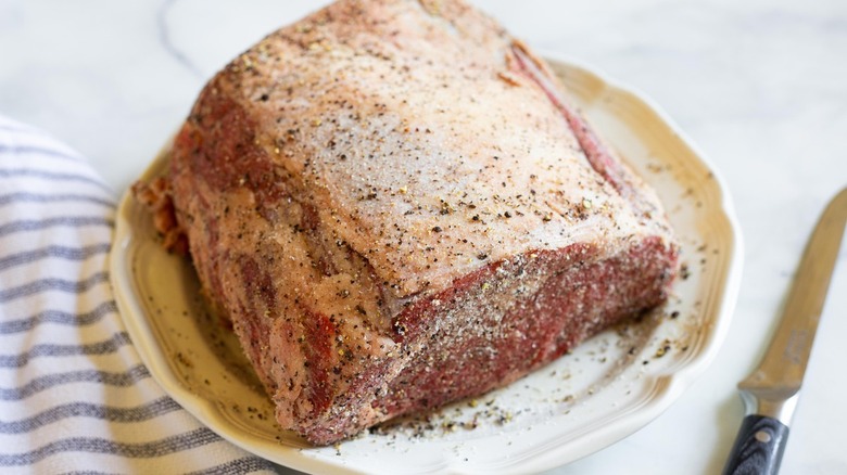 seasoned raw prime rib on a white plate 