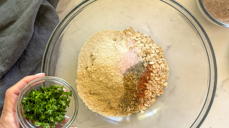 hand adding parsley to bowl