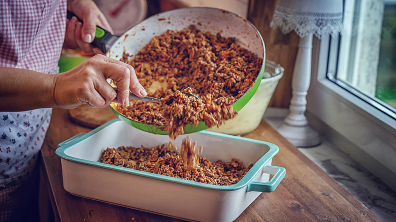 Ground beef being poured into dish