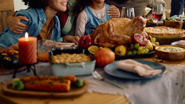 Family laughing at the dining table with turkey