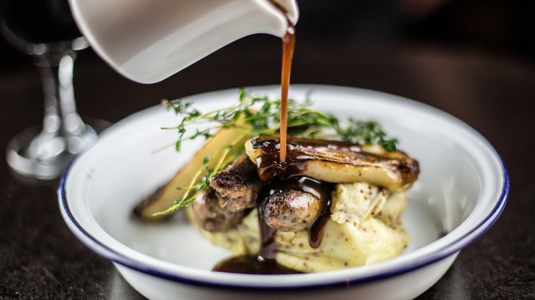 Pouring gravy over sausage and mash