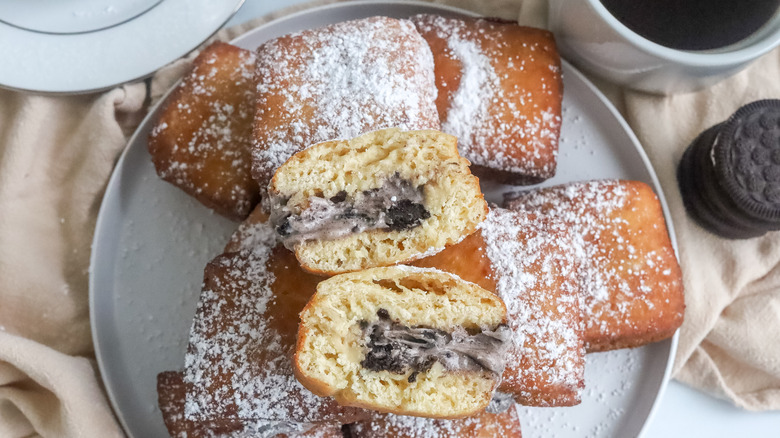 Cookies and cream beignets on plate with one cut in half