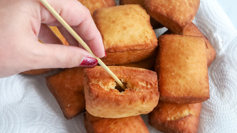 Wooden skewer poking hole in beignet