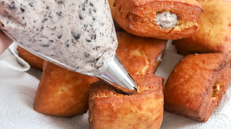 Beignets being filled with cookies and cream filling