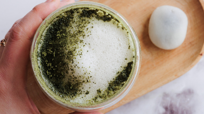 hand holding matcha latte with mochi