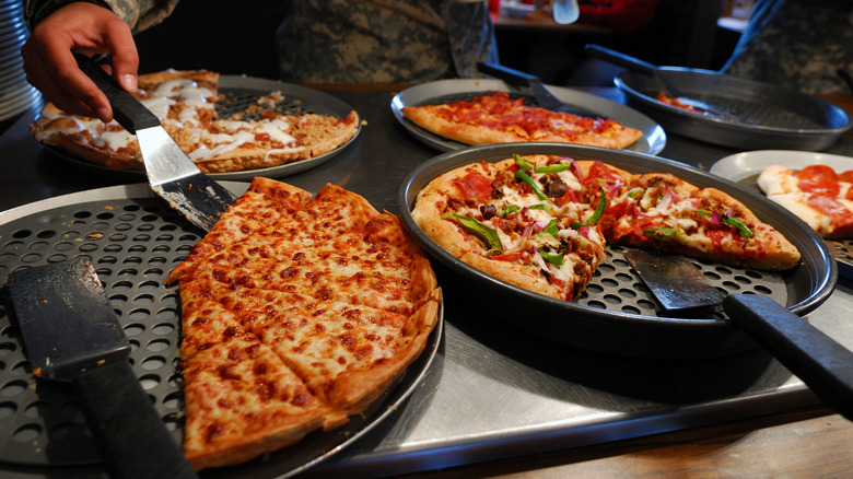 Various pizzas on display on a buffet line