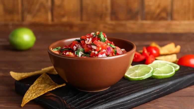 bowl of salsa with chips and lime slices