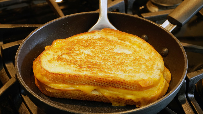 Grilled cheese on a spatula in a frying pan