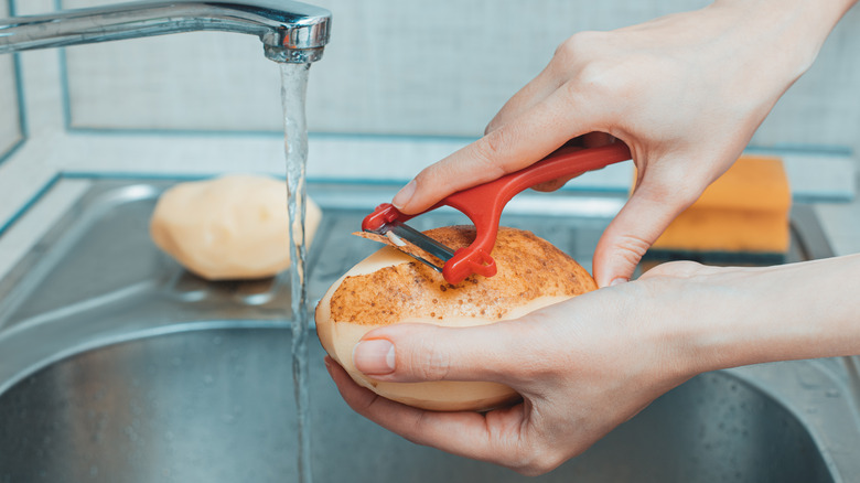 Home cook peeling a potato 