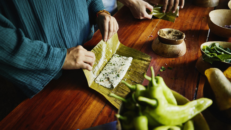 woman folding a fresh tamale