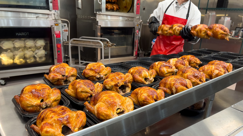 A Costco employee cooks various rotisserie chickens