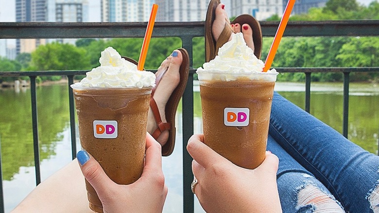 Two people holding dunkin' frozen coffees