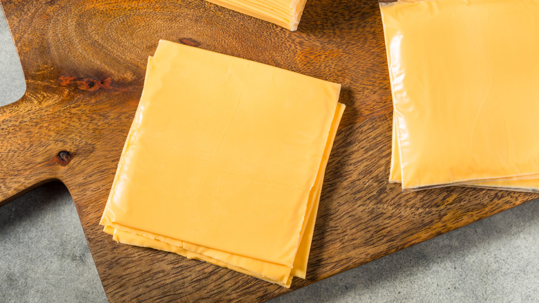 Slices of American cheese placed on a wooden cutting board