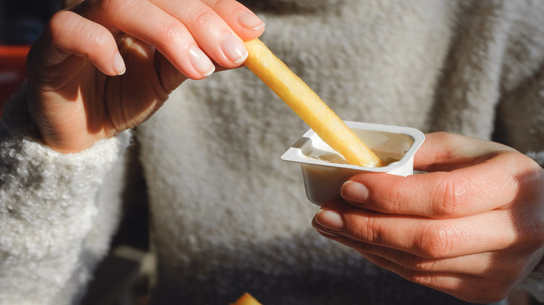 A person dipping fries into sauce.