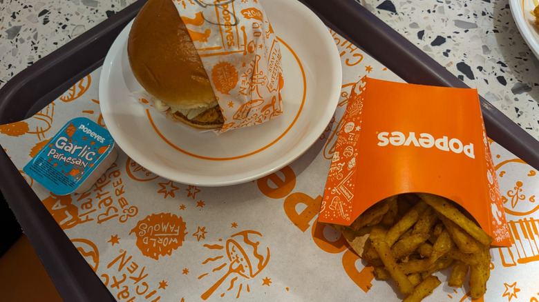 Popeyes chicken sandwich with fries and garlic parmesan sauce on tray