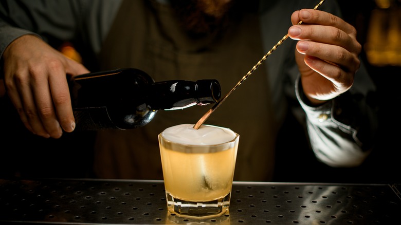 Bartender mixing drink with gold bar spoon