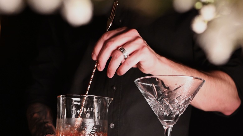 Bartender stirring drink with bar spoon