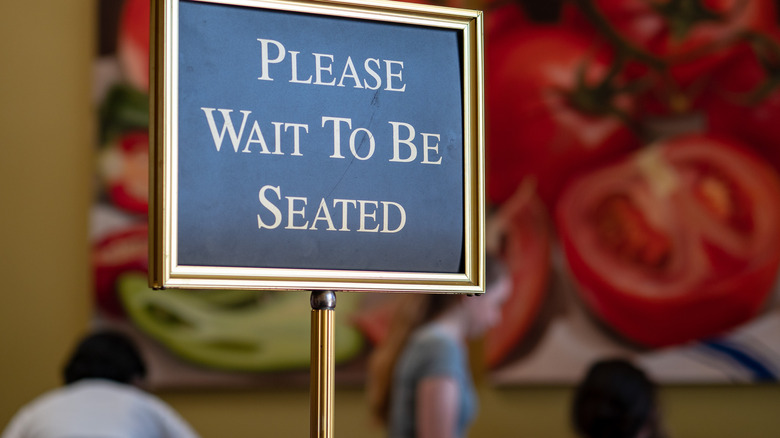 Sign that reads "Please wait to be seated"