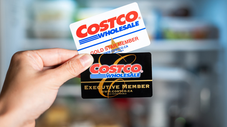 Hand holding two Costco membership cards