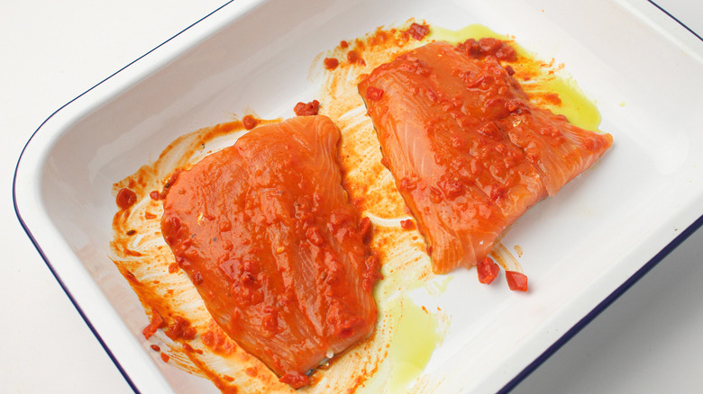 raw salmon filets brushed with harissa ni white baking dish