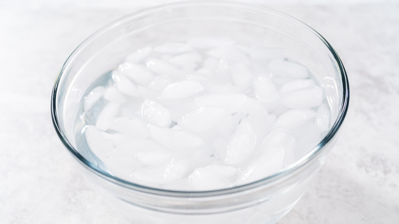 Classic ice bath made with glass bowl and ice on a white counter