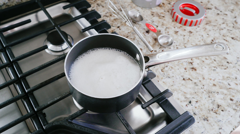 A pot filled with milk bubbling on the stove