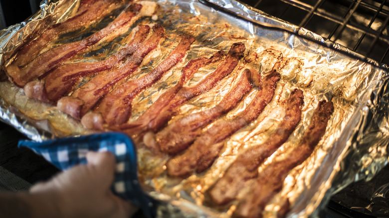 taking pan of bacon out of the oven