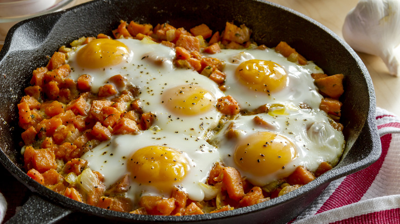 sweet potato hash topped with eggs in a skillet