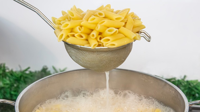 sieve scooping pasta from pot