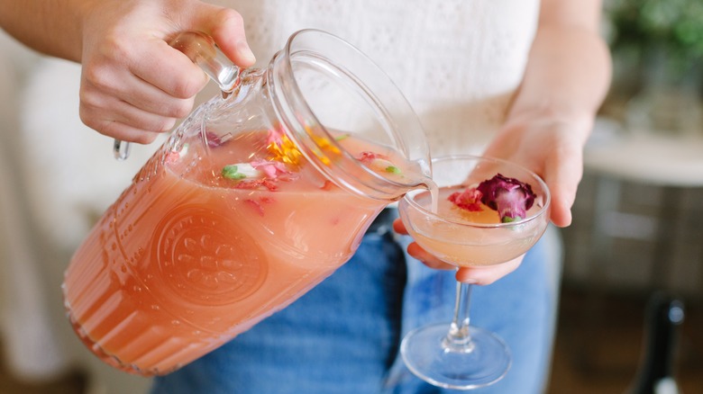 Woman's hands pouring cocktail from pitcher