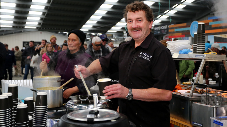 man serving soup at event