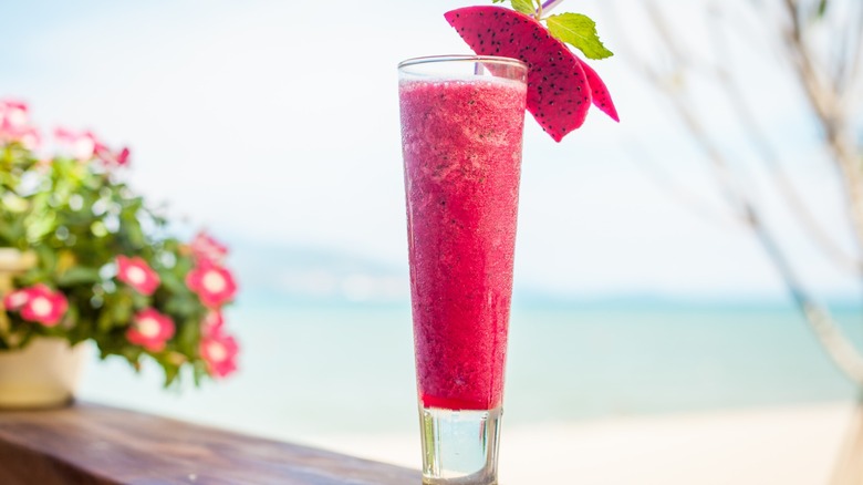 A pink dragon fruit cocktail at a beach