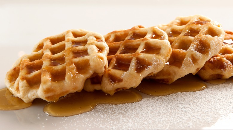 stacked waffles with syrup and powdered sugar