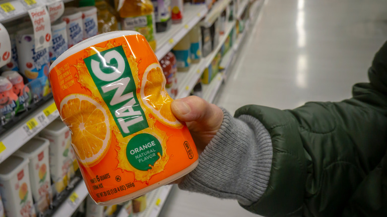 hand holding a jug of orange Tang