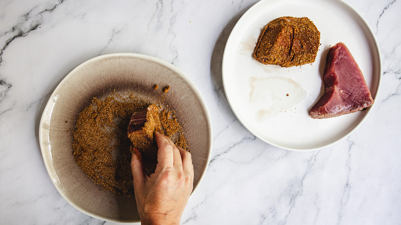 Coating tuna steaks in spice rub