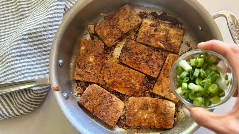 adding scallions to pan of tofu and sauce